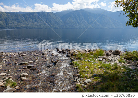 A tranquil lakeside setting featuring a flowing stream 126766850