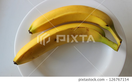 The peels of stale bananas lying on a white plate begin to rot 126767154