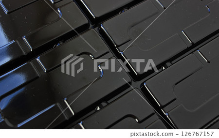 Niches and slots pressed into the black plastic surface Niches and slots pressed into the black plastic surface 126767157