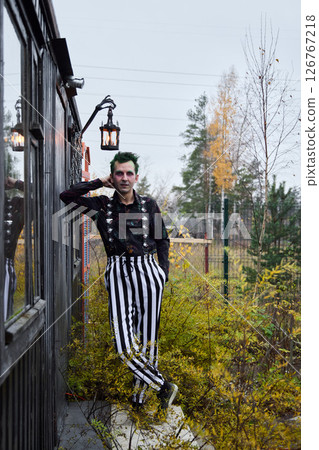 An Eccentric Clown Decked Out in Striped Attire Surrounded by Vibrant Autumn Foliage An Eccentric Clown Decked Out in Striped Attire Surrounded by Vibrant Autumn Foliage 126767218