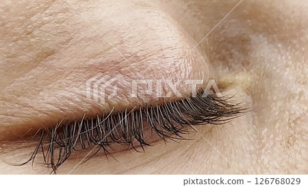 Focus on right green eye of attractive girl blinking and looking up. Portrait of a female pretty face. Calm facial expression of young woman. Tranquil sight of beautiful lady. 126768029