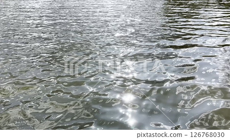 Scenery surface of pond illuminated by sun at summertime. Calm view on sea with small waves at sunny day. Beautiful summer nature landscape. Concept of tranquility scene. Slow motion 126768030