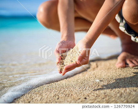 A child playing in the sand on a beach at a travel destination 126770924