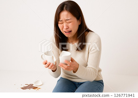 Woman crying over a broken mug on white background - stock photo 126771941