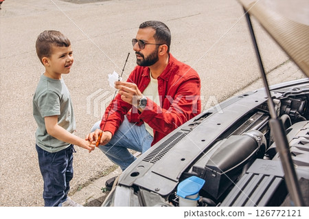 Father and sons repairing car together with the hood open. A heartfelt moment of bonding, fatherhood, parenting, teamwork, and learning. Celebrating Father Day through shared hands-on experience. 126772121