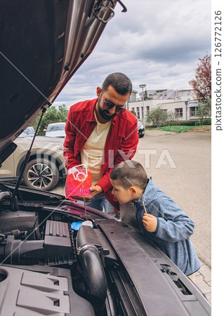 Father and sons repairing car together with the hood open. A heartfelt moment of bonding, fatherhood, parenting, teamwork, and learning. Celebrating Father Day through shared hands-on experience. 126772126