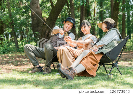 父母和孩子坐在戶外椅子上,微笑著看著智慧型手機,家人 父母和孩子坐在戶外椅子上,微笑著看著智慧型手機,家人 126773943