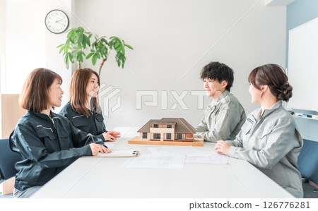 Male and female businessmen in the construction and building industry wearing work clothes holding a meeting, conference, and meeting using a house model 126776281