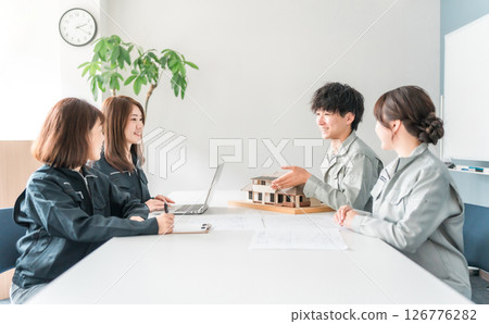Male and female businessmen in the construction and building industry wearing work clothes holding a meeting, conference, and meeting using a house model Male and female businessmen in the construction and building industry wearing work clothes holding a meeting, conference, and meeting using a house model 126776282