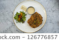 Crispy Breaded Cutlet with Fresh Salad and Citrus Dressing on a Marble Tabletop 126776857