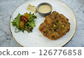 Crispy Breaded Cutlet with Fresh Salad and Citrus Dressing on a Marble Tabletop 126776858