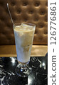 Refreshing iced latte in a tall glass served on a black marble table with a brown tufted leather background in a cozy cafe setting 126776861