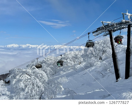 在晴朗的日子裡，長野縣滑雪勝地的滑雪纜車載著滑雪者，背景是野澤溫泉山脈 126777827