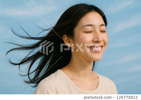 一位日本年輕女子的側面像,她感受著風,閉上眼睛,微笑著 一位日本年輕女子的側面像,她感受著風,閉上眼睛,微笑著 126778822