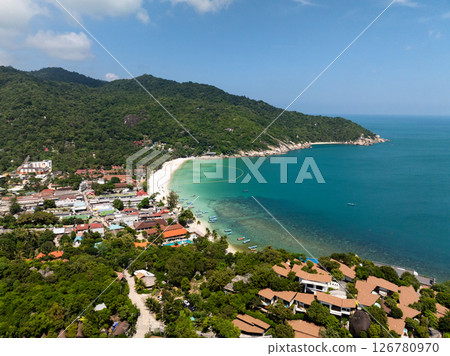 Coastal village featuring colorful boats on vibrant turquoise waters and surrounded by lush green hills. Haad Rin. Ko Pha Ngan, Thailand. Coastal village featuring colorful boats on vibrant turquoise waters and surrounded by lush green hills. Haad Rin. Ko Pha Ngan, Thailand. 126780970