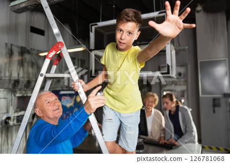 Boy pointing to something while trying to find solution of conundrum with relatives in quest room Boy pointing to something while trying to find solution of conundrum with relatives in quest room 126781068