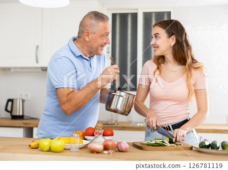 Happy father spending time with adult daughter - preparing lunch together in kitchen 126781119