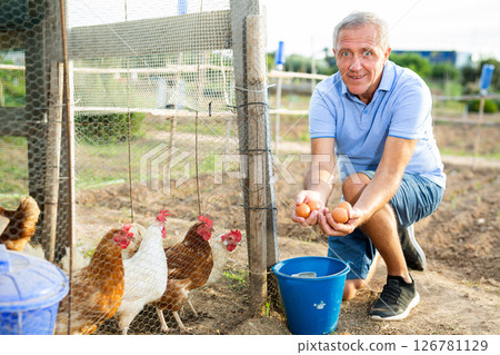 Man collecting chicken egg outdoors 126781129