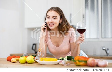 Woman chatting with friends on the phone in cozy home kitchen Woman chatting with friends on the phone in cozy home kitchen 126781161