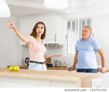 Domestic quarrel between elderly father and adult daughter in kitchen Domestic quarrel between elderly father and adult daughter in kitchen 126781208