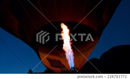 Powerful gas burners inflating a balloon create a spectacular scene against the backdrop of a twilight sky in Cappadocia, Turkey. Lighting the flame of a large balloon in the dark. Turkish travel trip Powerful gas burners inflating a balloon create a spectacular scene against the backdrop of a twilight sky in Cappadocia, Turkey. Lighting the flame of a large balloon in the dark. Turkish travel trip 126781771