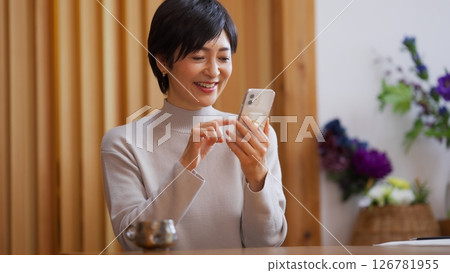 一位 50 多歲的女性正在操作智慧型手機 126781955