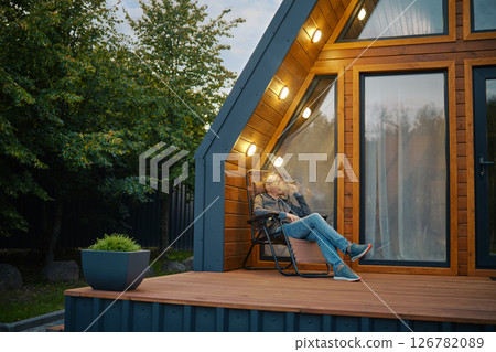 A relaxed man sits thoughtfully at sunset on the terrace and smokes a cigar 126782089