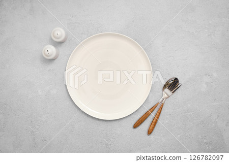 Overhead view of empty plate next to spoon, fork and salt and pepper shakers Overhead view of empty plate next to spoon, fork and salt and pepper shakers 126782097