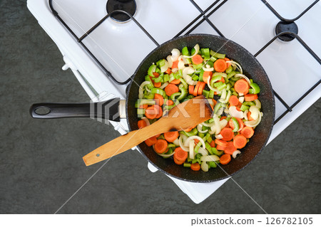 Cooking fresh vegetables in a skillet on a stovetop during an afternoon meal preparation 126782105