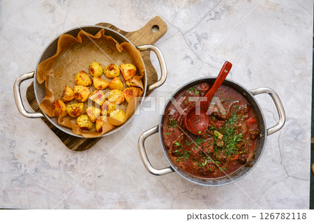 Delicious beef stew served with golden roasted potatoes in a rustic kitchen setting 126782118