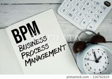 BPM Business Process Management text on paper notebook page with alarm clock and calculator on wooden background BPM Business Process Management text on paper notebook page with alarm clock and calculator on wooden background 126782620
