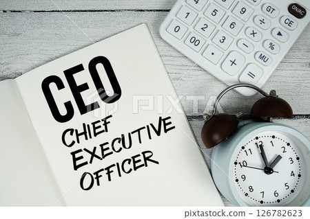 CFO Chief Executive Officer text on paper notebook page with alarm clock and calculator on wooden background 126782623