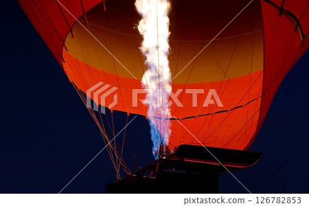 Strong flames inflate a bright red hot air balloon. A flight in Cappadocia. Turkey travel. Flames of a large fire and a balloon glowing in the dark. Tourist tour, Turkish culture, majestic journey Strong flames inflate a bright red hot air balloon. A flight in Cappadocia. Turkey travel. Flames of a large fire and a balloon glowing in the dark. Tourist tour, Turkish culture, majestic journey 126782853