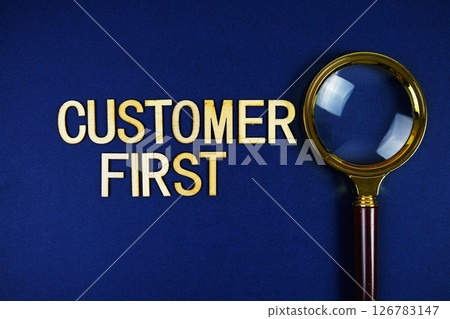Customer First alphabet letters with magnifying glass on navy blue background 126783147