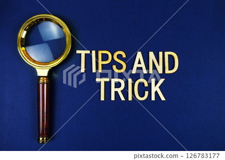 Tips and Trick alphabet letters with magnifying glass on navy blue background 126783177