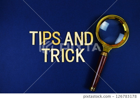 Tips and Trick alphabet letters with magnifying glass on navy blue background 126783178