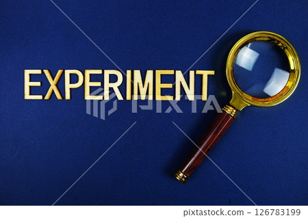 Experiment alphabet letters with magnifying glass on navy blue background 126783199