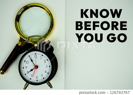 Know Before You Go text with magnifying glass and alarm clock flat lay on notepad background Know Before You Go text with magnifying glass and alarm clock flat lay on notepad background 126783767