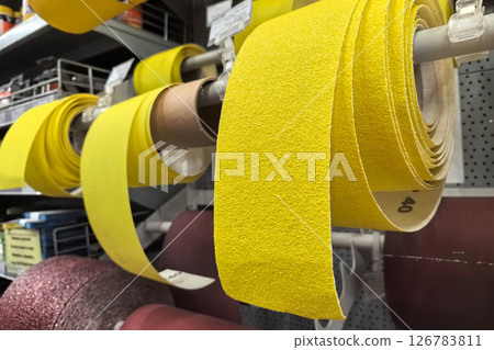 Bright yellow sandpaper rolls showcased in a well-organized workshop display Bright yellow sandpaper rolls showcased in a well-organized workshop display 126783811