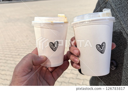Two cups of coffee with heart designs shared between friends outdoors Two cups of coffee with heart designs shared between friends outdoors 126783817
