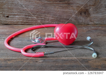Red heart and a pink stethoscope on wood table. Red heart and a pink stethoscope on wood table. 126783847