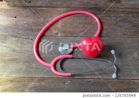 Red heart and a pink stethoscope on wood table. Red heart and a pink stethoscope on wood table. 126783849