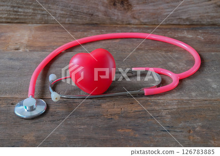 Red heart and a pink stethoscope on wood table. Red heart and a pink stethoscope on wood table. 126783885