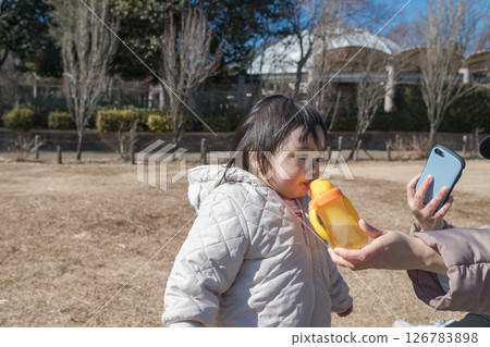 【相模原市麻溝公園，一名一歲小孩和媽媽在草地上玩耍，補充水分】 126783898