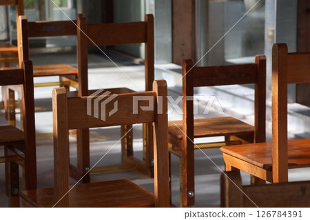 A classroom with rows of small wooden chairs A classroom with rows of small wooden chairs 126784391