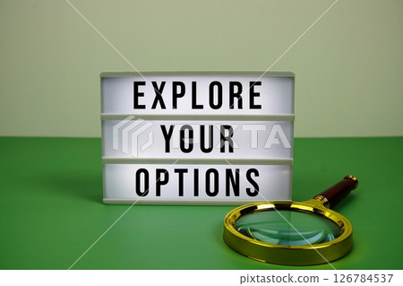 Explore Your Options text on light box with magnifying glass on green background 126784537