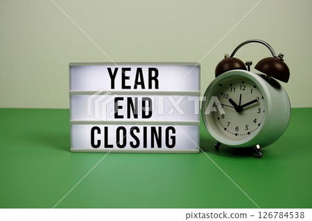Year End Closing text on light box with alarm clock on green background 126784538
