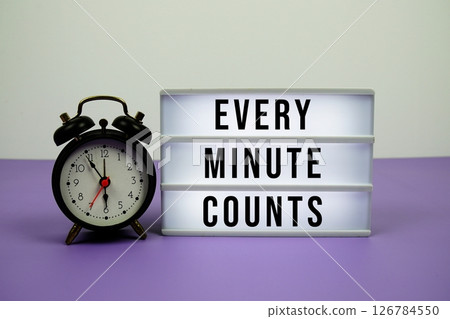 Every Minute Counts text on light box with alarm clock on purple background 126784550