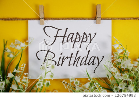 Happy Birthday text on paper card with flower blooming decoration on yellow background 126784998