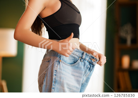 A young woman is trying on big jeans 126785830